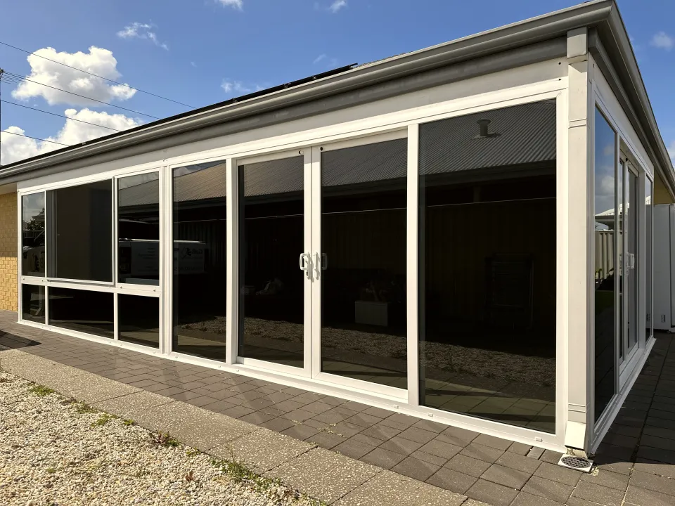 White patio enclosure with fixed glazing panels onto a gravel path