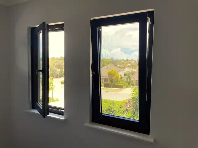 Anthracite tilt-and-turn windows, one sash swung open on side hinges